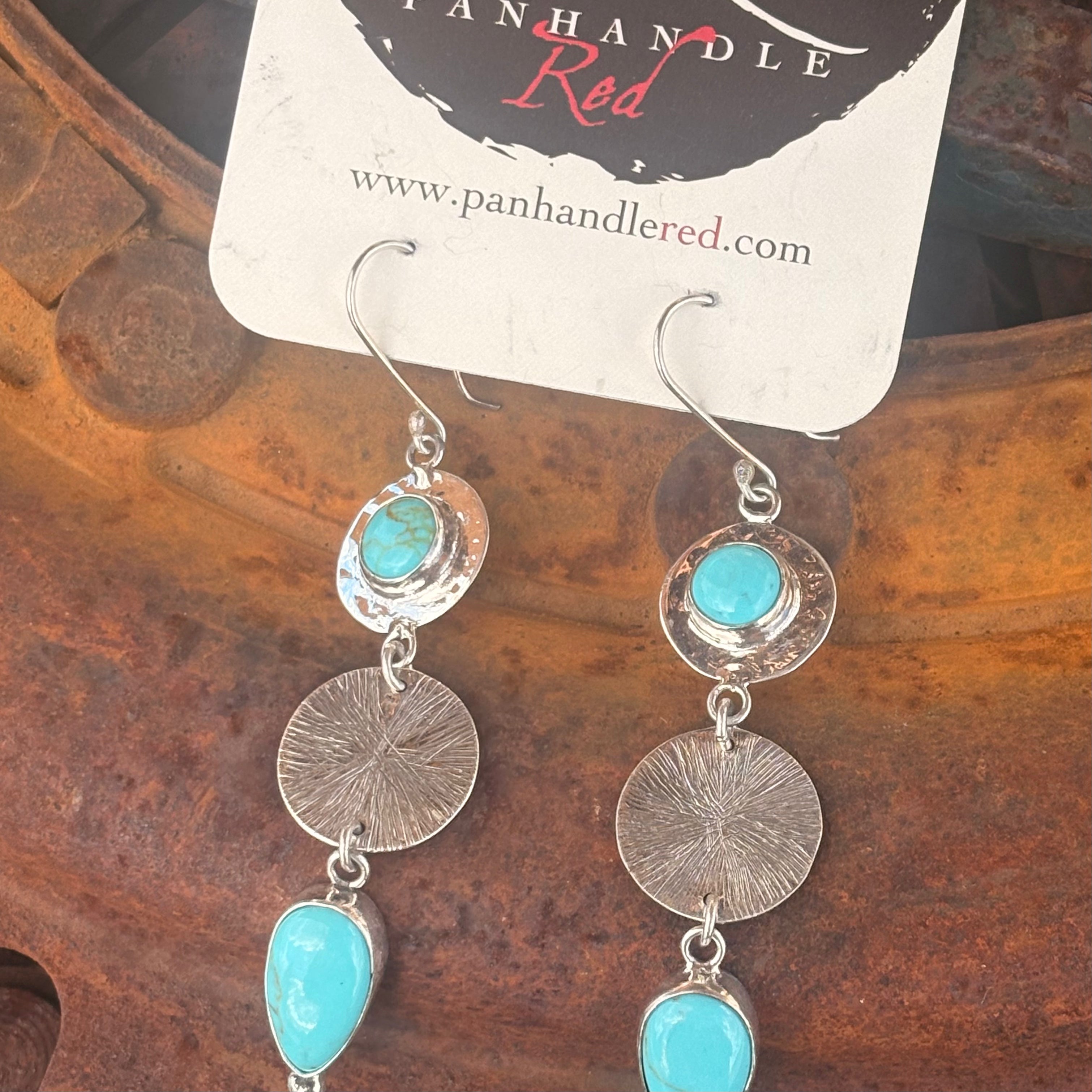 Silver earrings with turquoise stones on a Panhandle Red branded card.